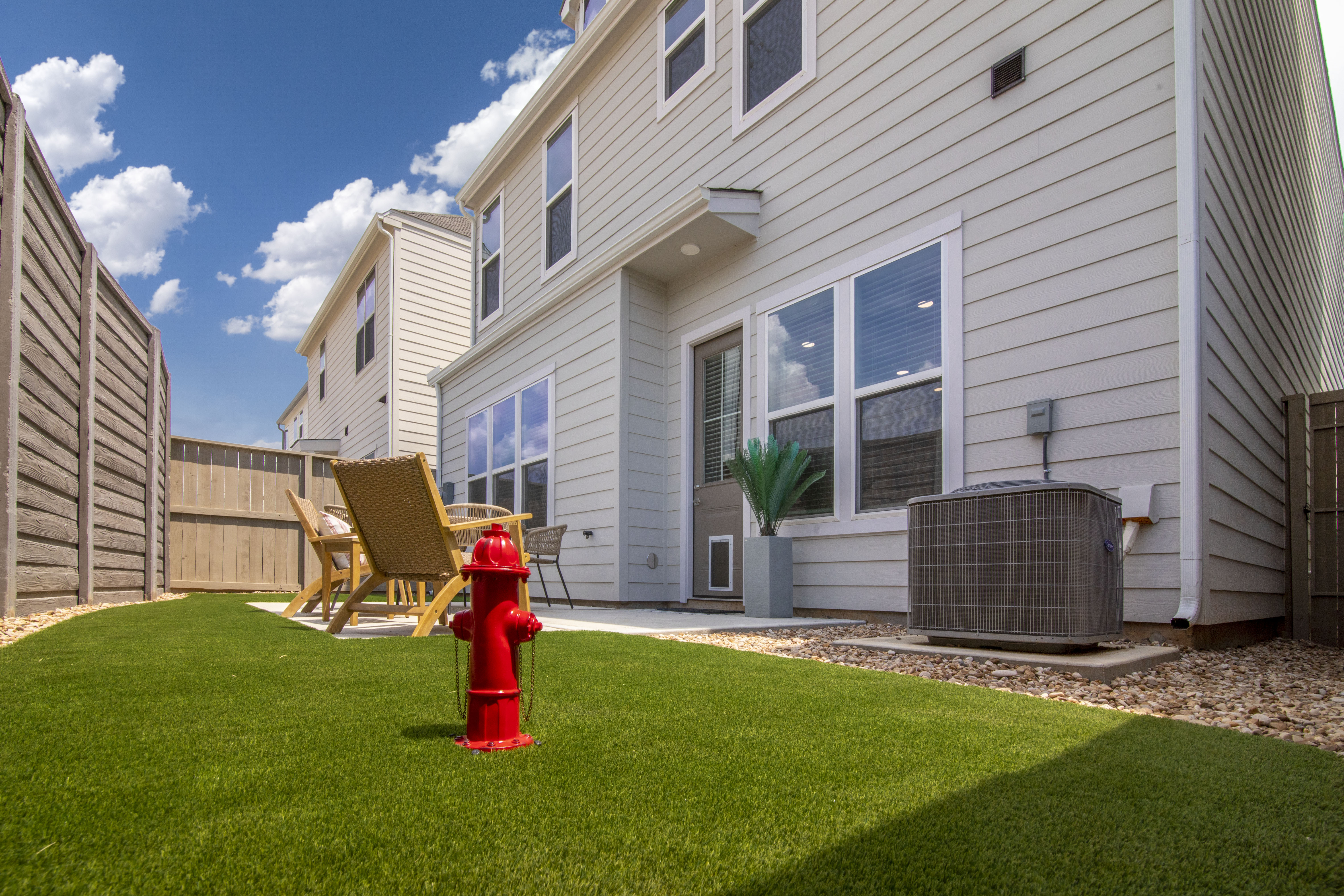 Private backyard with a green lawn and wooden fence.